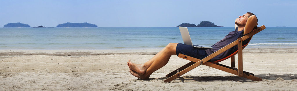 Man sitting on beach reclining with laptop