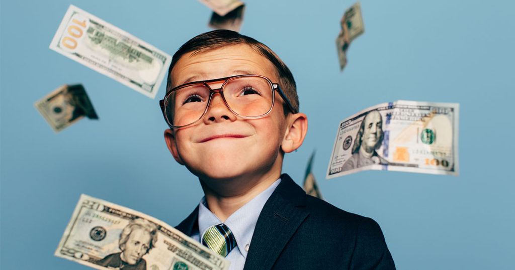 Young boy posing with money drifting around him